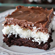 a piece of chocolate cake on a plate with white frosting and coconut toppings