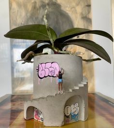 a potted plant sitting on top of a table next to a wall with graffiti