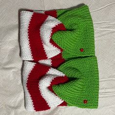 two green and white knitted hats laying on top of each other next to each other