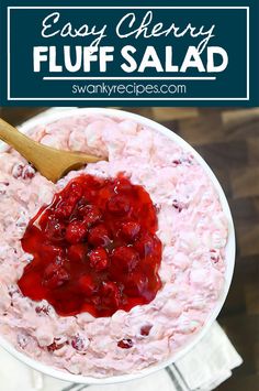 a bowl filled with strawberry fluff salad next to a wooden spoon