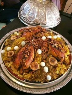 a large platter filled with lots of food on top of a black table next to a silver plate