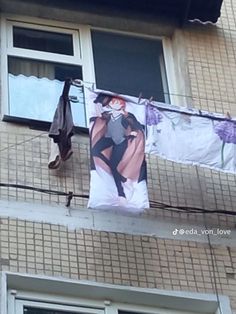 two clothes hanging from a line on the side of a building next to an open window