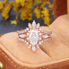 a close up of a ring on top of a velvet box with flowers in the background