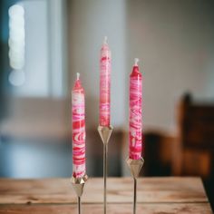 three pink candles sitting on top of a wooden table