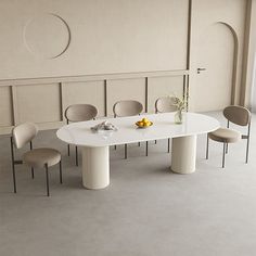 a white table with four chairs and a vase on it next to a wall in an empty room