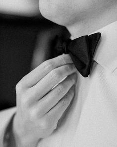 black and white photograph of a man wearing a bow tie with his hands on his chest