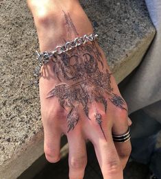 a person's hand with a tattoo on it and a chain around the wrist