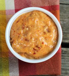 a white bowl filled with sauce on top of a checkered table cloth