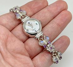 A gorgeous Precious Time sterling silver ladies wristwatch with mother of pearl dial with roman numerals. The bracelet part in a lovely butterfly and flower design, set with moonstones and amethyst. Maker/Markings: Marked 925 SILVER Condition: Very Good Used Condition. The watch works and keeps good time - Please look at photos Measurements: 7.25" long - Dial 16mm - Case 21mm Weight: 37.1g Amethyst Butterfly, Funky Jewellery, Butterfly And Flower, Butterfly Flower, Funky Jewelry, Women Wrist Watch, Butterfly Flowers, Design Set, Roman Numerals