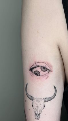 a bull skull and eye tattoo on the left thigh