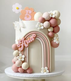 a three tiered cake decorated with flowers and balloons