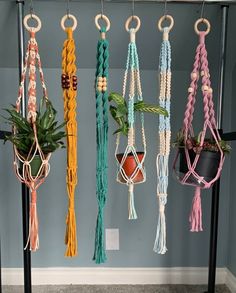 macrame plant hangers with plants in them hanging on a rack next to a wall