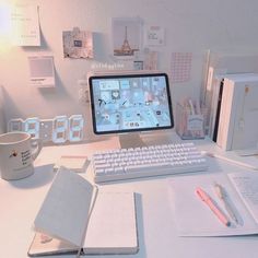 a desktop computer sitting on top of a desk next to a cup and notebooks