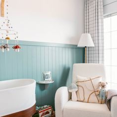 a baby's room with a white chair and blue walls