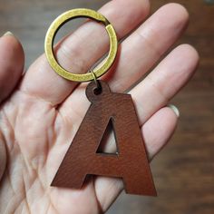 a wooden keychain with a letter on it in someone's hand,