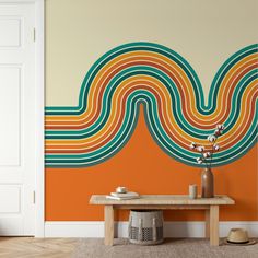 an orange and green striped wall in a living room with a wooden table on the floor