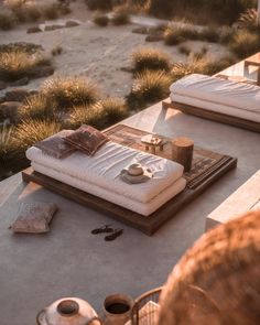 an outdoor living area with white couches and coffee table in the foreground, surrounded by desert scrubbery