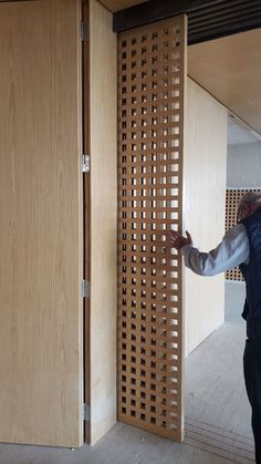 a man standing in front of a wooden door with perforated panels on it