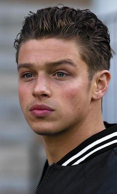 a close up of a person wearing a jacket and looking at the camera with a serious look on his face