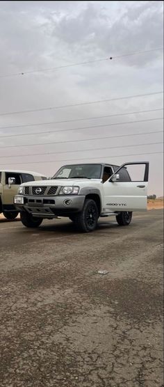 two pickup trucks parked next to each other in a parking lot on a cloudy day