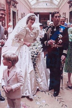 a man and woman in wedding attire standing next to a little boy wearing a suit