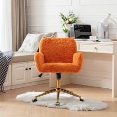 an orange chair sitting on top of a white rug in front of a desk with a laptop