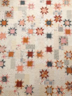 an old quilt with many different colors and designs on the front, along with several small stars