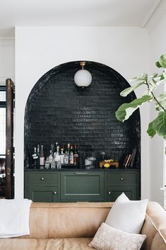 a living room filled with furniture next to a brick wall covered in bottles and glasses