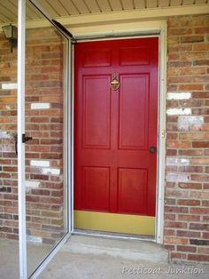 a red door is open in front of a brick building