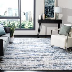 a living room with a couch, chair and rug on the floor in front of a window