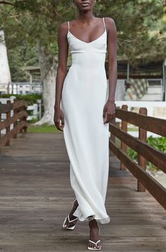 a woman in a white dress walking down a wooden walkway