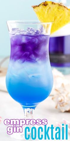 a blue and purple drink in a glass with a pineapple on top