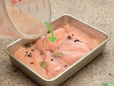 a metal container filled with meat and seasoning next to a measuring cup on top of a counter