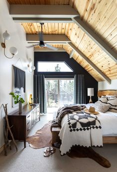 a bedroom with a large bed and wooden ceiling