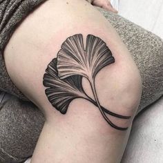 a black and white ginko tree leaf tattoo on the thigh