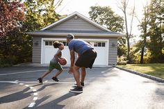 a man and child playing basketball in a driveway