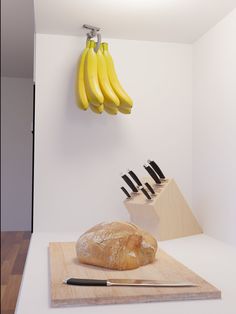 a loaf of bread sitting on top of a cutting board next to knifes and bananas