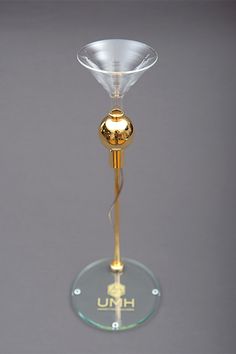 a gold colored wine glass on a clear base with the word unh underneath it