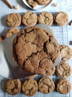 a cookie is being held up by a spatula on a cooling rack with more cookies in the background