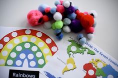 colorful pom poms are placed on top of a map and rainbows stickers