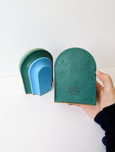 a hand holding a green and blue toaster next to it's open box