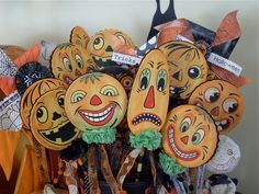 a bunch of pumpkins with faces on them sitting in a basket next to other halloween decorations