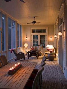 a long table with candles on it sitting in front of some chairs and windows next to a door