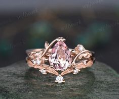 an engagement ring with a pink stone surrounded by white diamonds on top of a rock