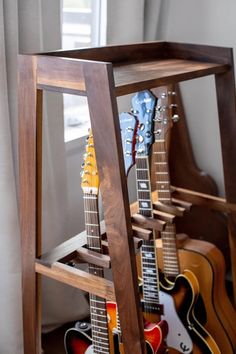 the guitar stand is made out of wood and holds several different types of electric guitars