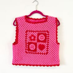 a pink crocheted top hanging on a wall