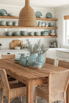 a wooden table surrounded by wicker chairs and blue vases with plants in them