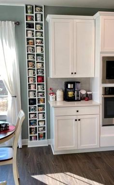 a kitchen with white cabinets and gray walls, wood flooring and wooden table in the center