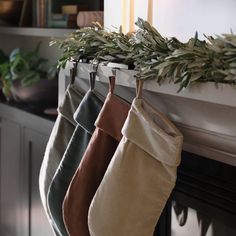 three stockings hanging from a mantle with greenery