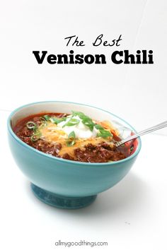 the best venison chili recipe is in a blue bowl with a silver spoon